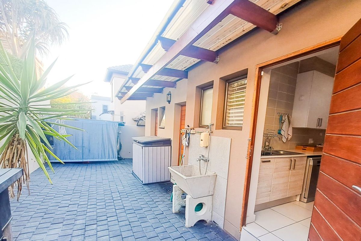 Rear courtyard area featuring paved flooring, a covered timber pergola, and an external utility sink, with direct access to the kitchen.