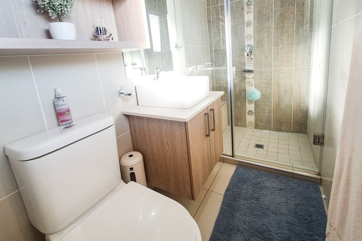 A modern bathroom featuring a glass-enclosed shower, a contemporary vanity with a vessel sink, and a wall-mounted toilet.