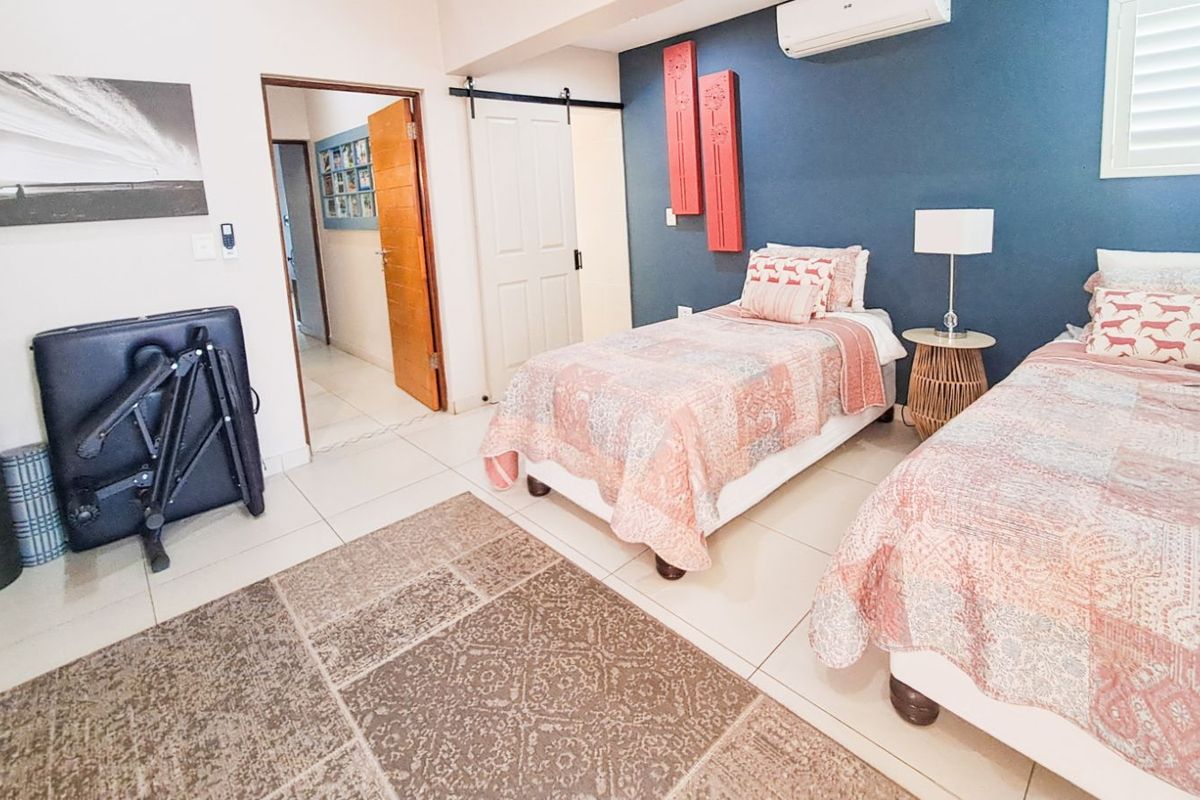A bedroom featuring tiled flooring, a blue accent wall, a sliding barn-style door, and a wall-mounted air conditioning unit.