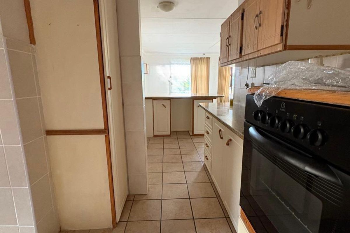 A dated kitchen featuring tiled flooring, built-in cabinetry, and a freestanding oven, offering a functional layout with potential for modernization.