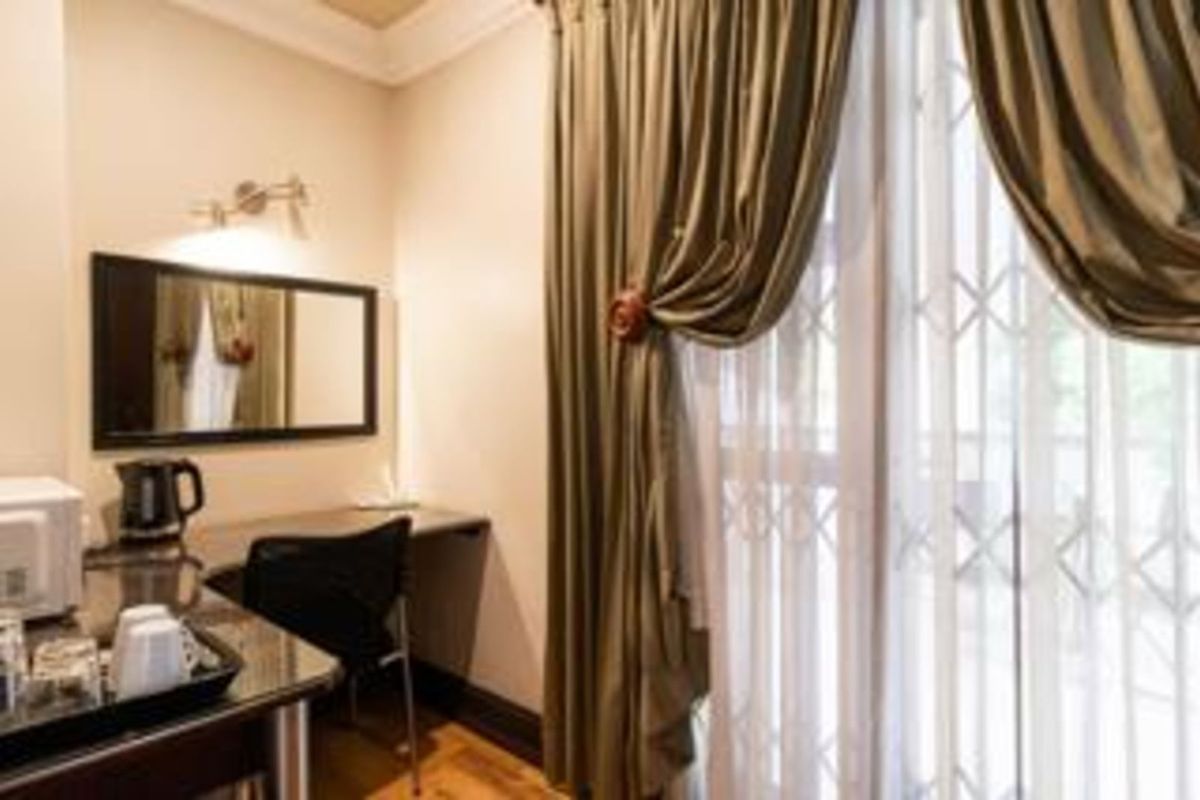 A functional bedroom space featuring a built-in desk area, wall-mounted lighting, and sliding glass doors with security gates leading to an outdoor area.