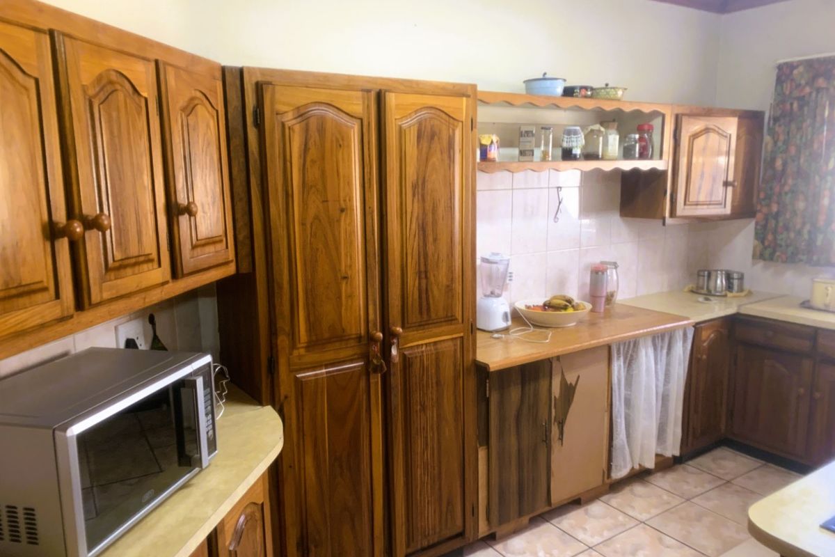 A traditional kitchen featuring solid wood cabinetry, laminate countertops, tiled backsplash, and tiled flooring, offering a classic layout with ample storage space.
