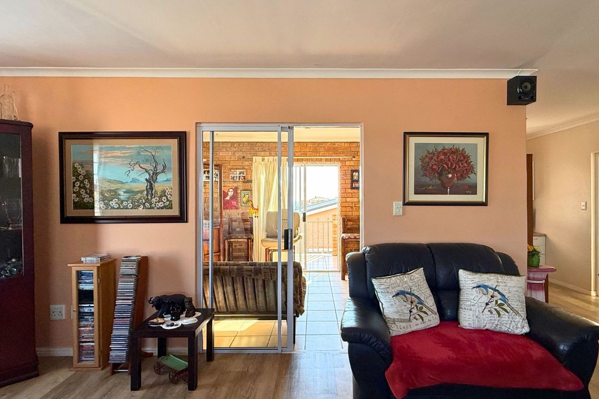Living room featuring laminate flooring and a sliding glass door providing access to an adjoining sunroom or patio area.