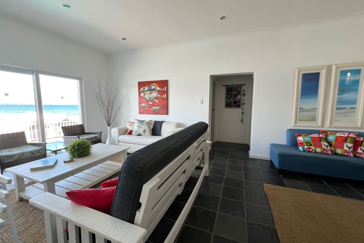 Spacious living area featuring dark slate flooring, recessed ceiling lighting, and large sliding glass doors offering direct ocean views.