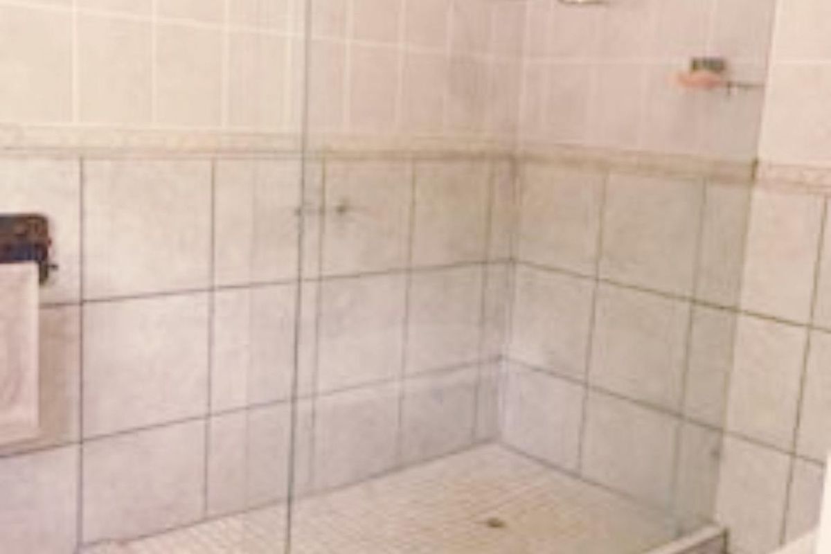 A functional bathroom shower area featuring a glass enclosure, tiled walls, and a tiled shower base.