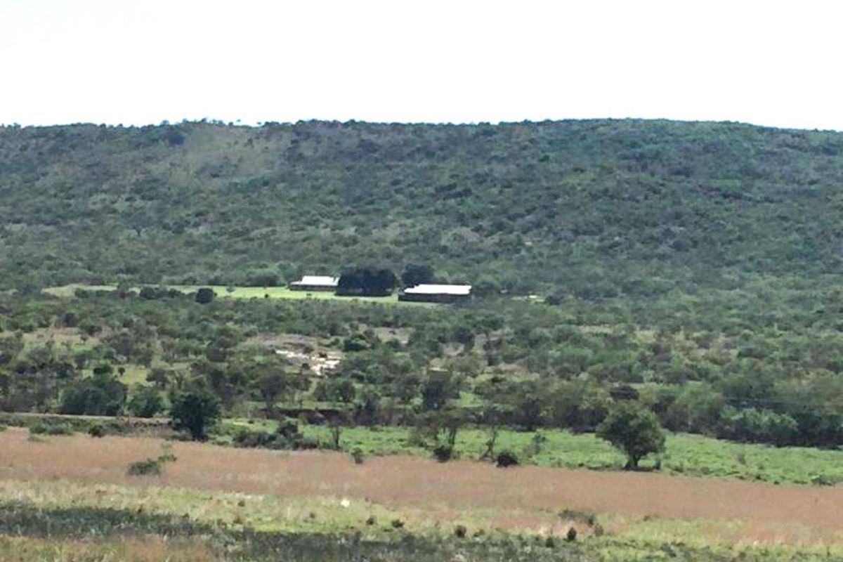 A distant aerial view of the farm property, showcasing the main buildings nestled within the expansive natural landscape and surrounding vegetation.