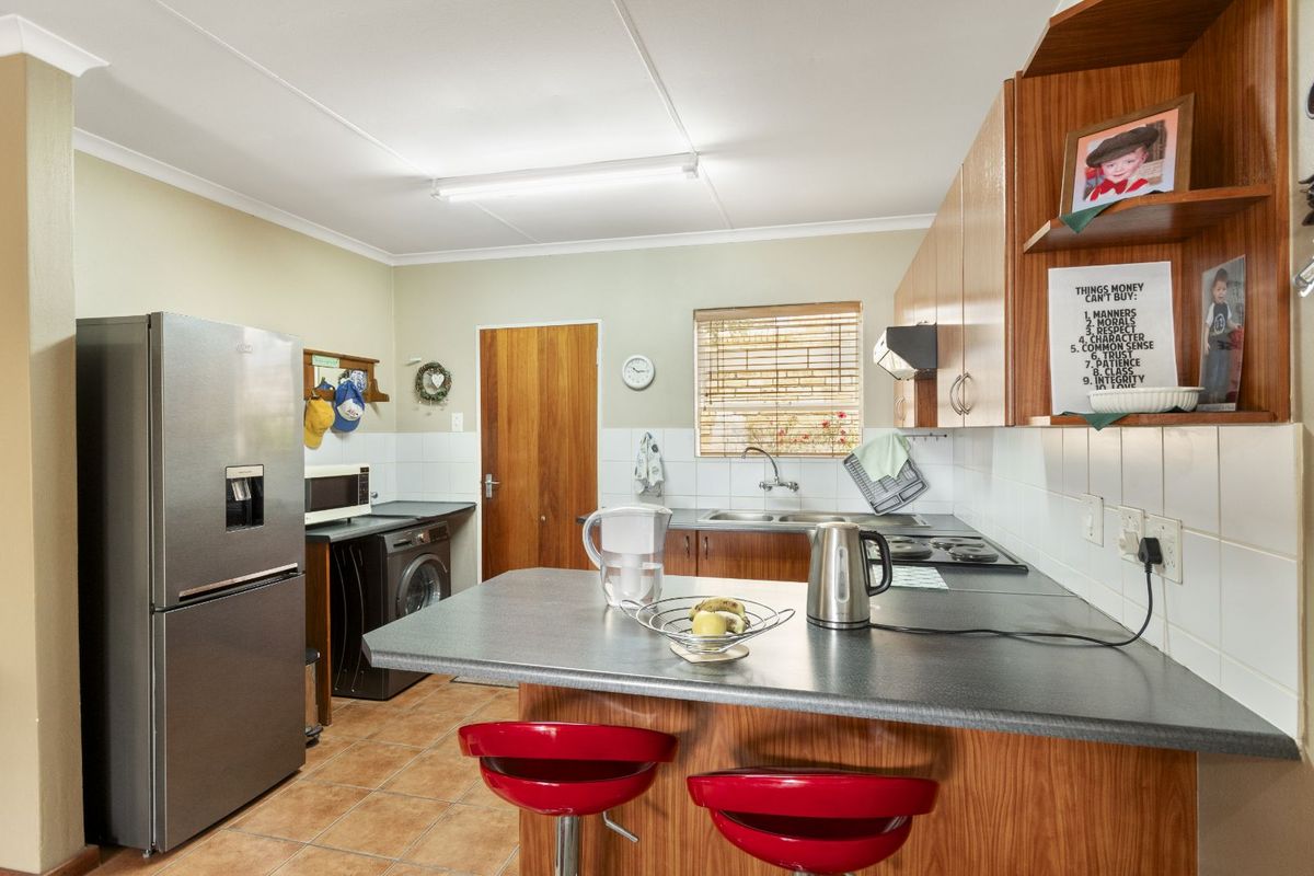 Functional kitchen featuring wood-look cabinetry, laminate countertops, a double sink, and integrated hob, offering a practical layout for daily meal preparation.