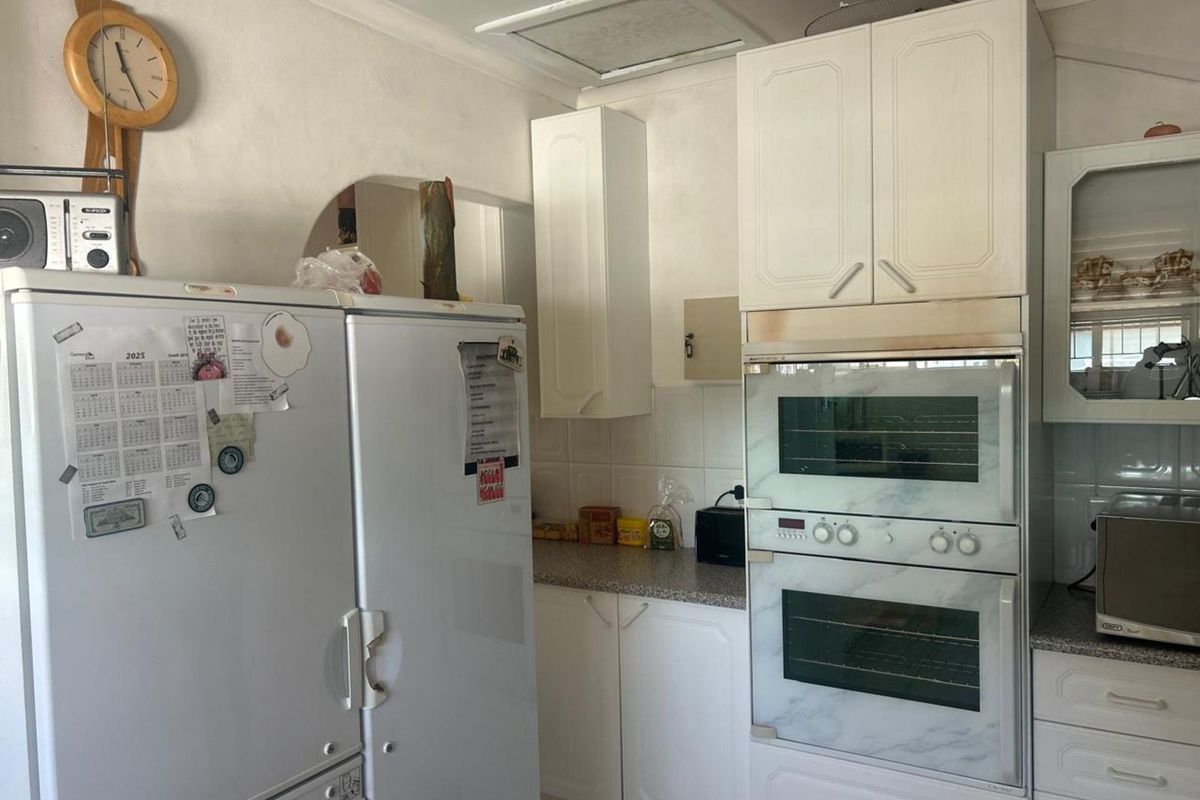 A functional kitchen featuring white cabinetry, a built-in double oven, and tiled splashbacks, offering a practical layout for daily meal preparation.