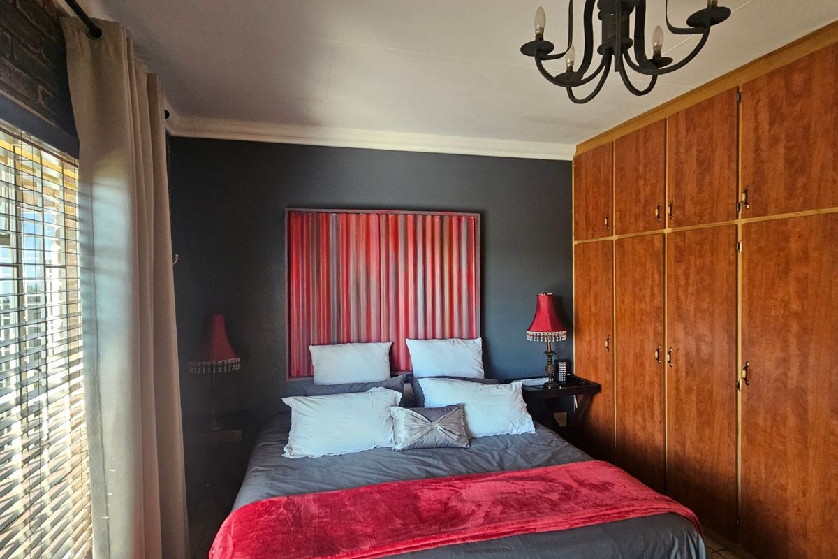 A bedroom featuring built-in wooden cabinetry, dark accent wall, and a classic chandelier fixture.