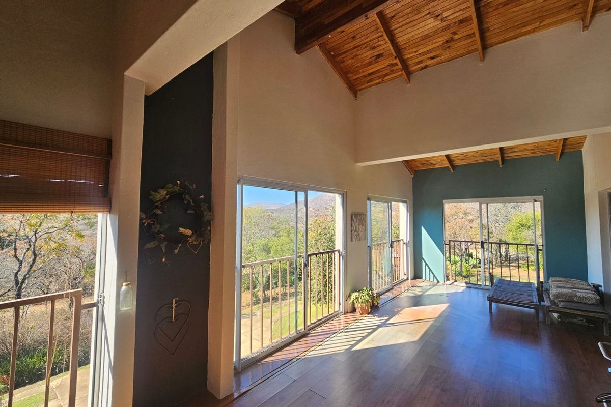 Spacious living area featuring high vaulted timber ceilings, large sliding glass doors, and expansive views of the surrounding landscape.
