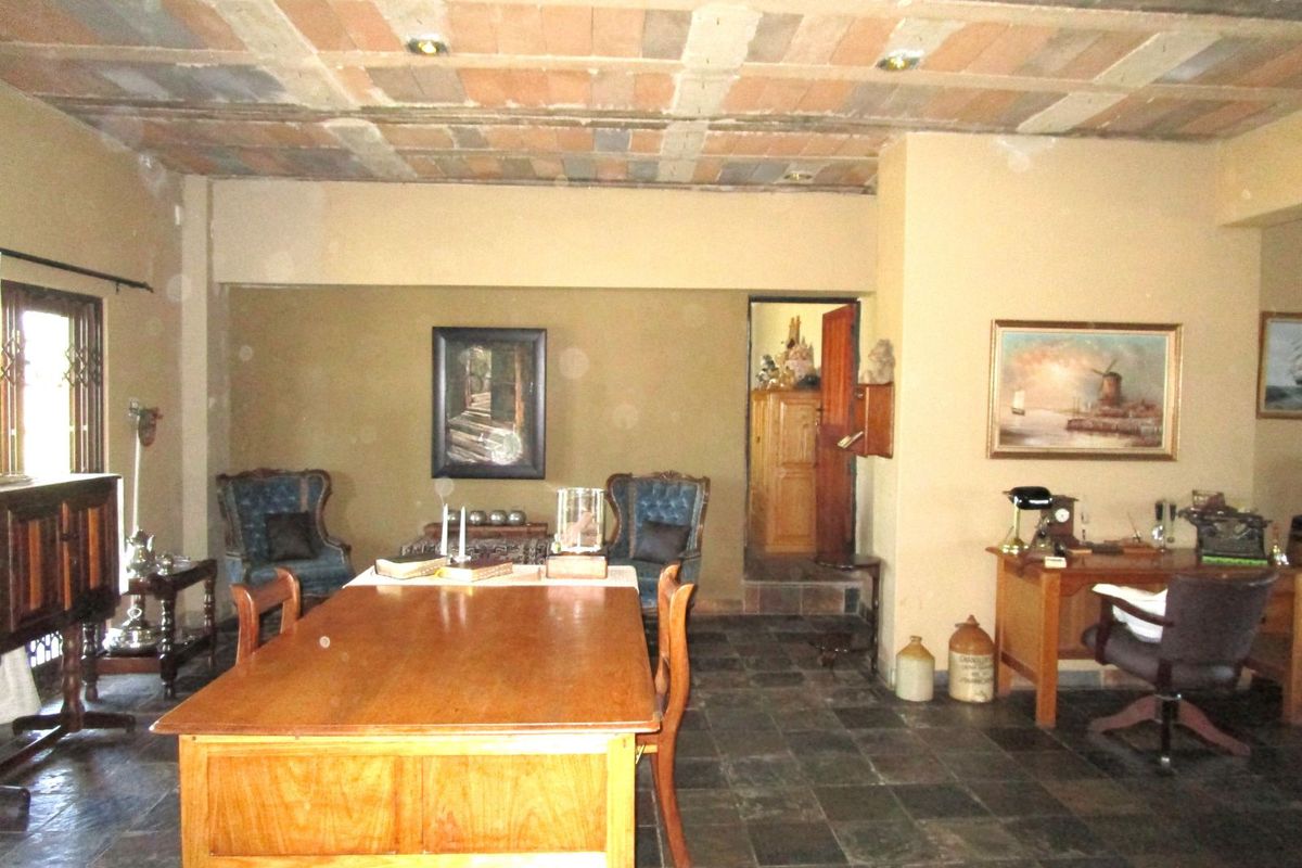 Spacious living area featuring rustic exposed brick ceiling, slate tile flooring, and a traditional layout with access to an adjoining room.