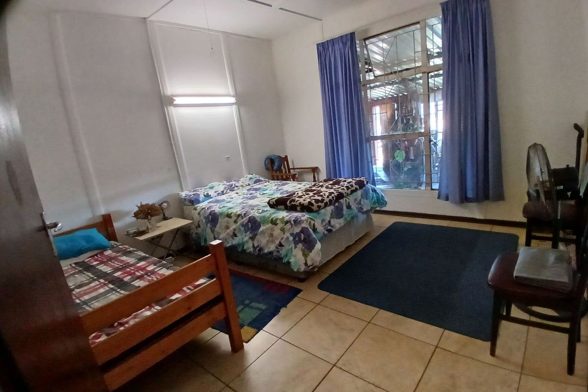 A spacious bedroom featuring tiled flooring, large windows with curtains, and built-in lighting fixtures, offering a functional and comfortable living space.
