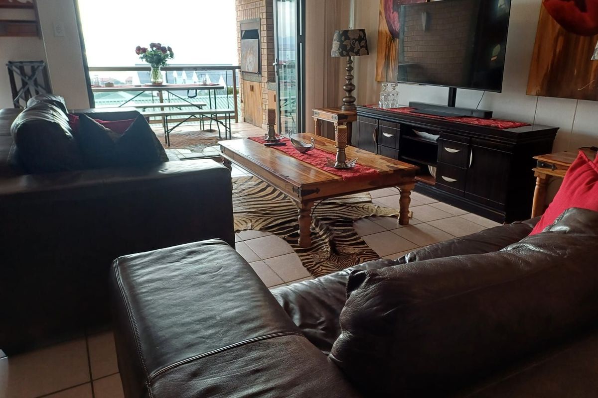 Spacious living area featuring tiled flooring, leading directly onto a covered balcony with an outdoor built-in braai area.