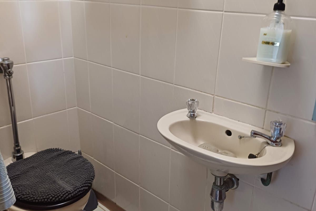 A compact bathroom featuring a wall-mounted basin and a standard toilet with full-height wall tiling.