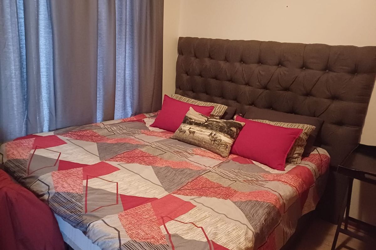 A bedroom featuring neutral walls and laminate flooring, providing a functional and comfortable sleeping space.