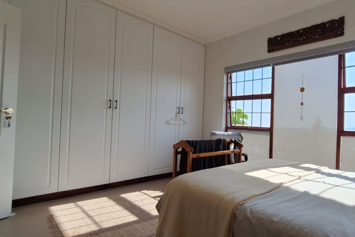 A bright bedroom featuring extensive built-in white cabinetry, large windows with grid detailing, and neutral flooring, offering a clean and functional living space.