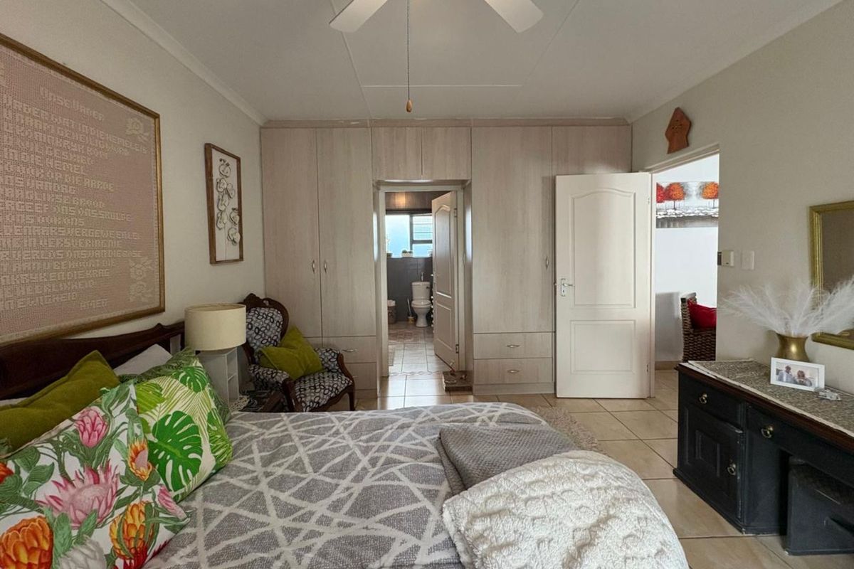 A well-maintained bedroom featuring built-in cabinetry, tiled flooring, and an en-suite bathroom access.