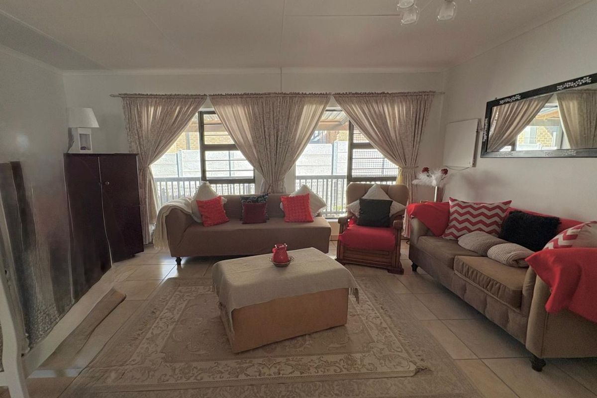 A spacious living room featuring tiled flooring and large windows that provide natural light, creating a comfortable and functional living space.