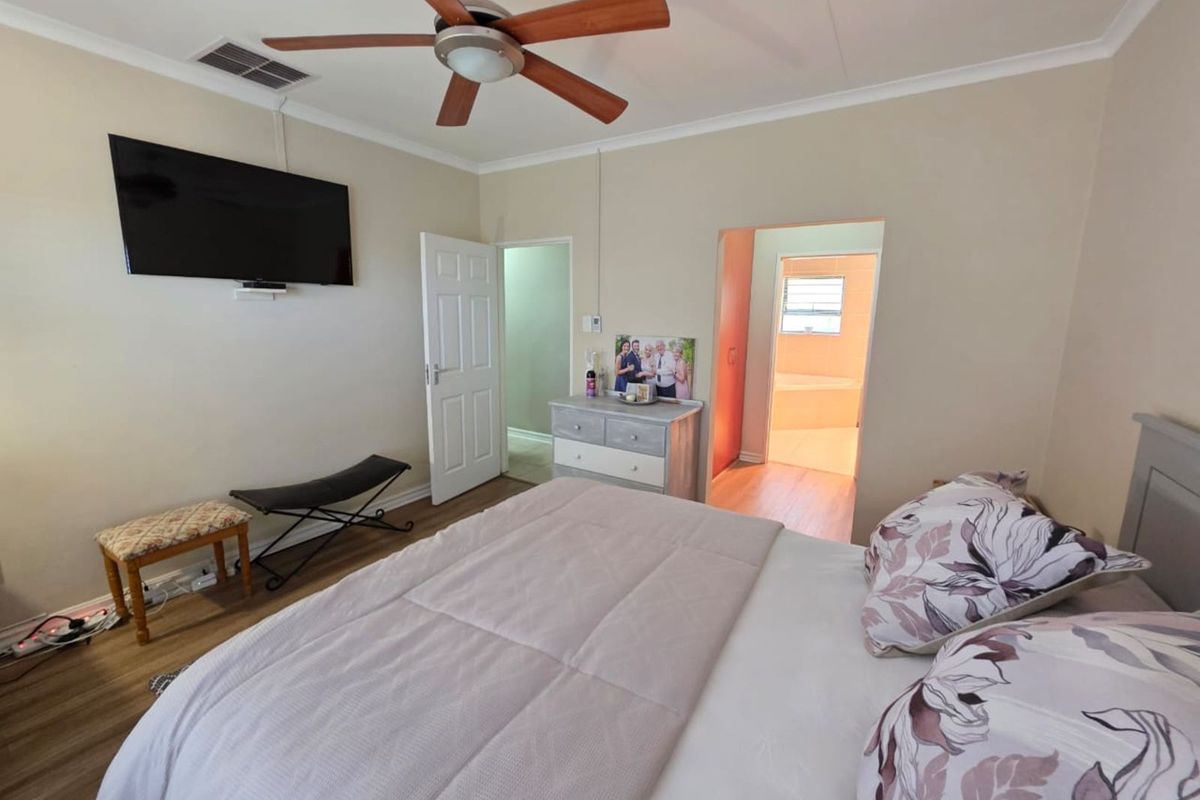 A well-maintained bedroom featuring a ceiling fan, laminate flooring, and direct access to an adjoining bathroom.