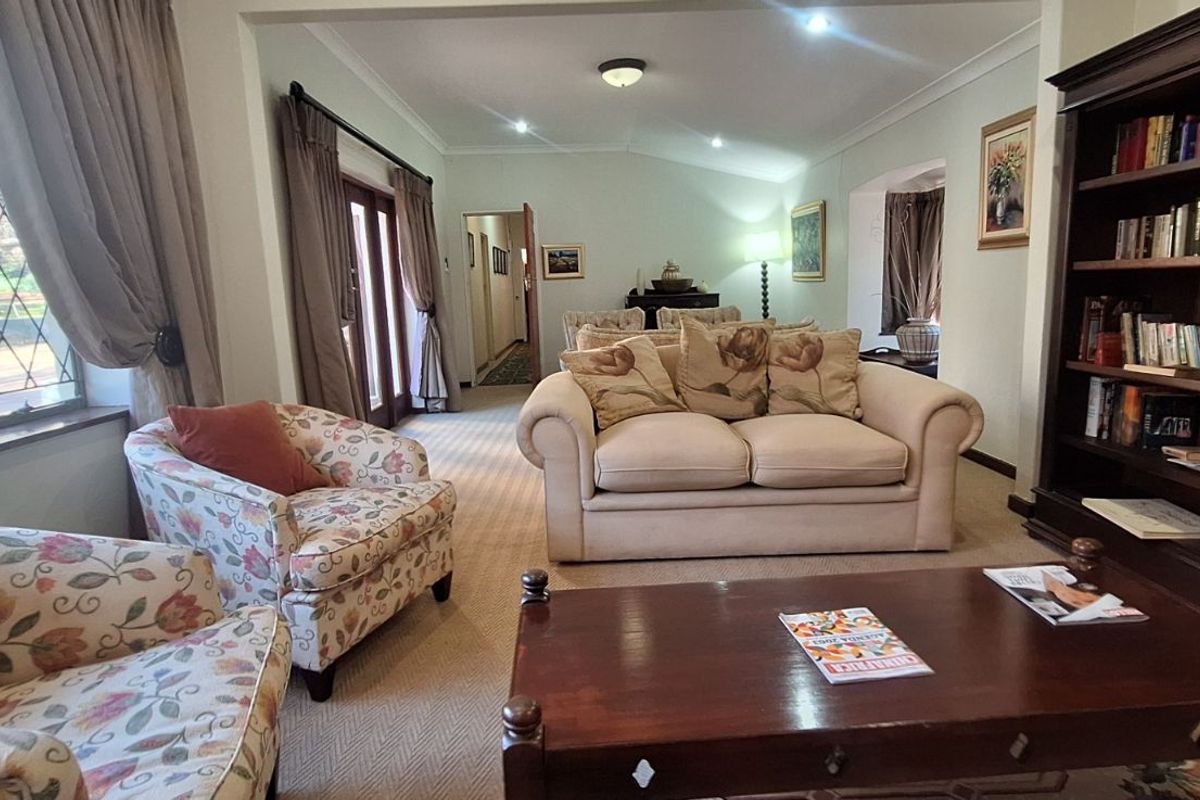 A spacious living room featuring large windows, carpeted flooring, and built-in wooden shelving, offering a comfortable and well-lit area.