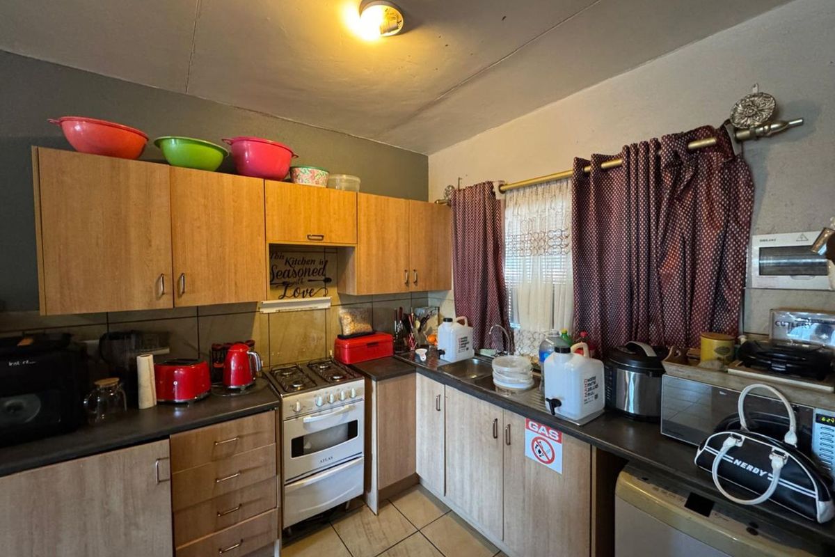 Compact kitchen featuring wood-look cabinetry, a gas stove, and tiled flooring, offering a functional layout with potential for modernization.