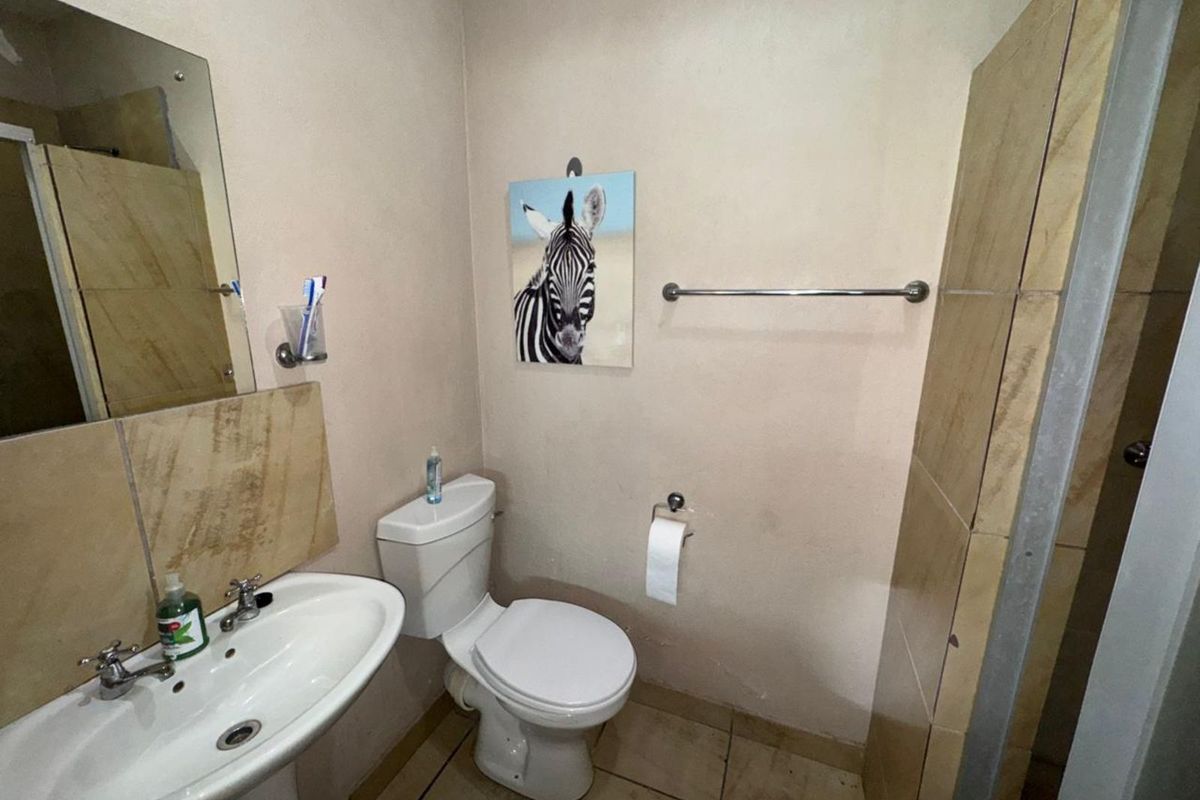 A functional bathroom featuring a pedestal basin, a standard toilet, and a tiled shower enclosure with neutral finishes.