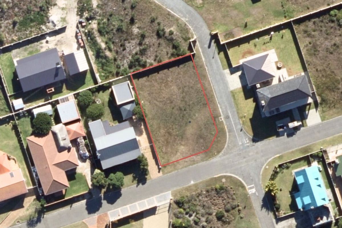 An aerial view of a vacant residential plot in a developed neighborhood, clearly outlined in red, showing surrounding properties and street access.