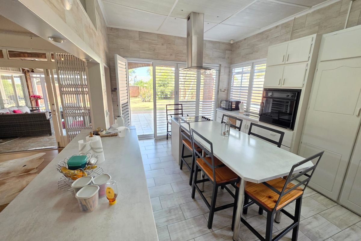 Spacious kitchen featuring a central island, built-in oven, extractor fan, and tiled flooring, with direct access to the outdoor patio area.