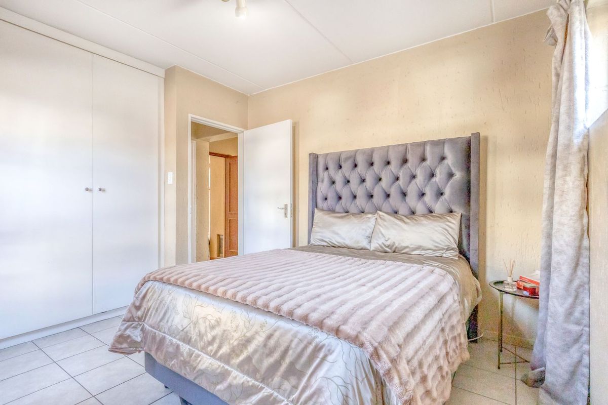 A bedroom featuring built-in cupboards and tiled flooring, providing a functional and neutral living space.