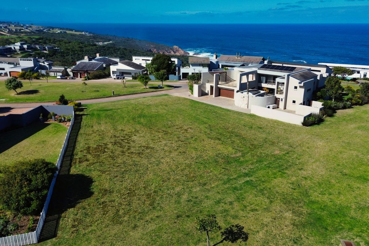 An aerial view of a vacant residential plot in a coastal estate, showcasing the surrounding neighborhood and proximity to the ocean.