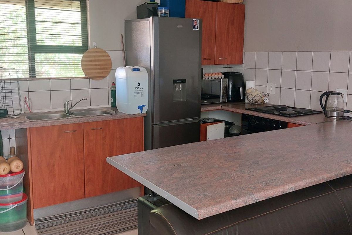Functional kitchen featuring laminate countertops, wood-finish cabinetry, a built-in hob, and a tiled backsplash, offering a practical layout for daily meal preparation.