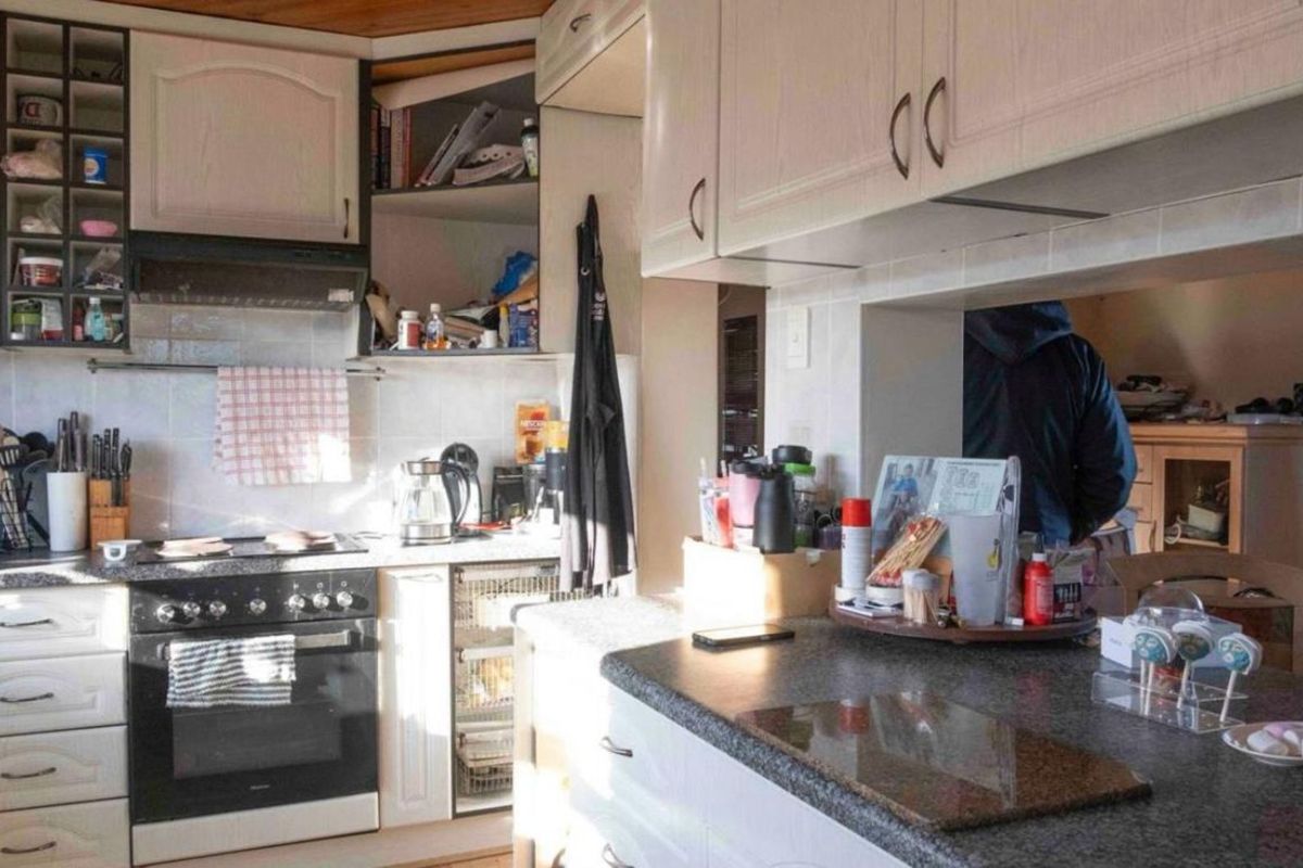 A functional kitchen featuring built-in cabinetry, a freestanding oven with extractor fan, and a breakfast bar counter overlooking the adjacent living area.