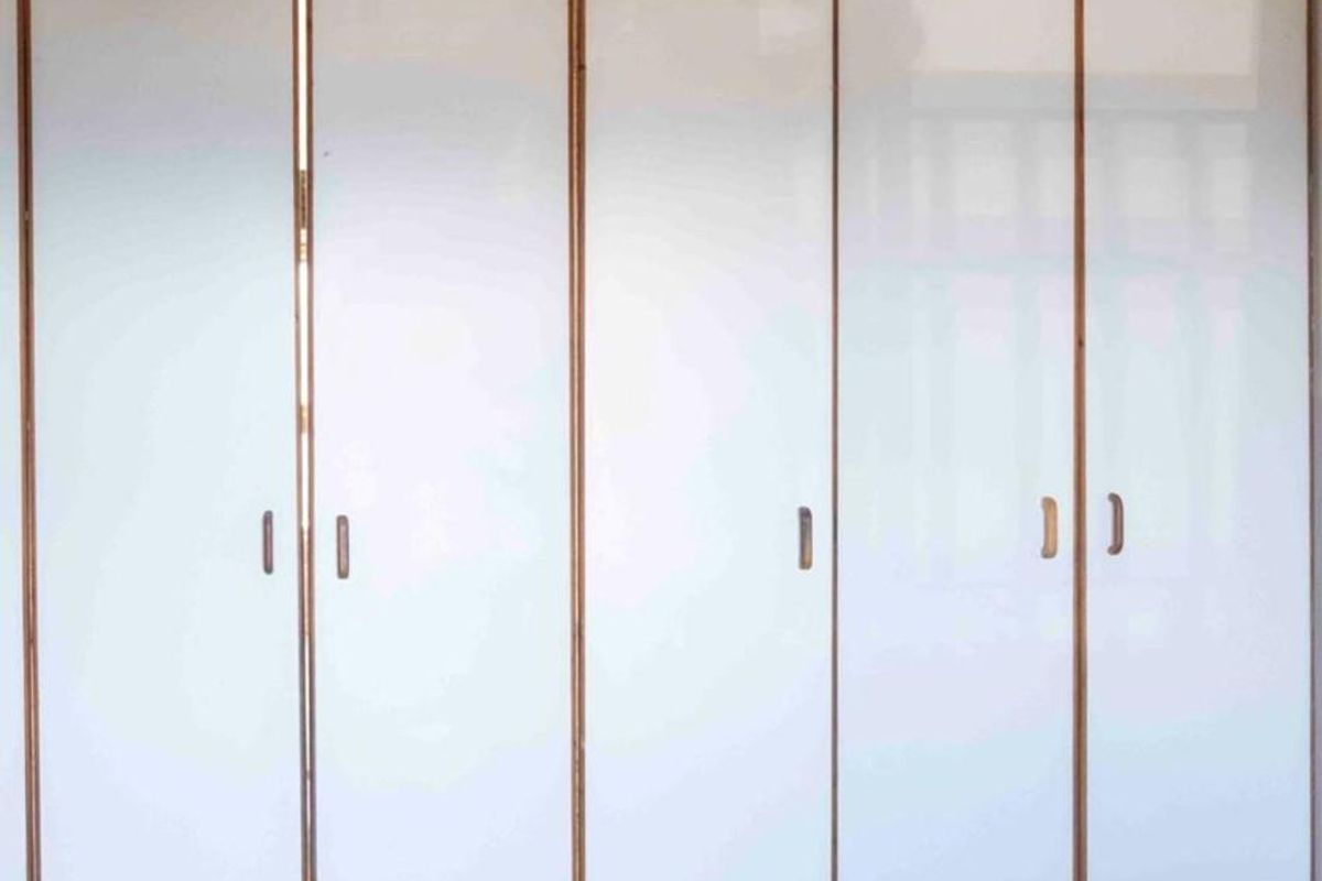A bedroom featuring floor-to-ceiling built-in wardrobes with white panel doors and a ceiling fan.