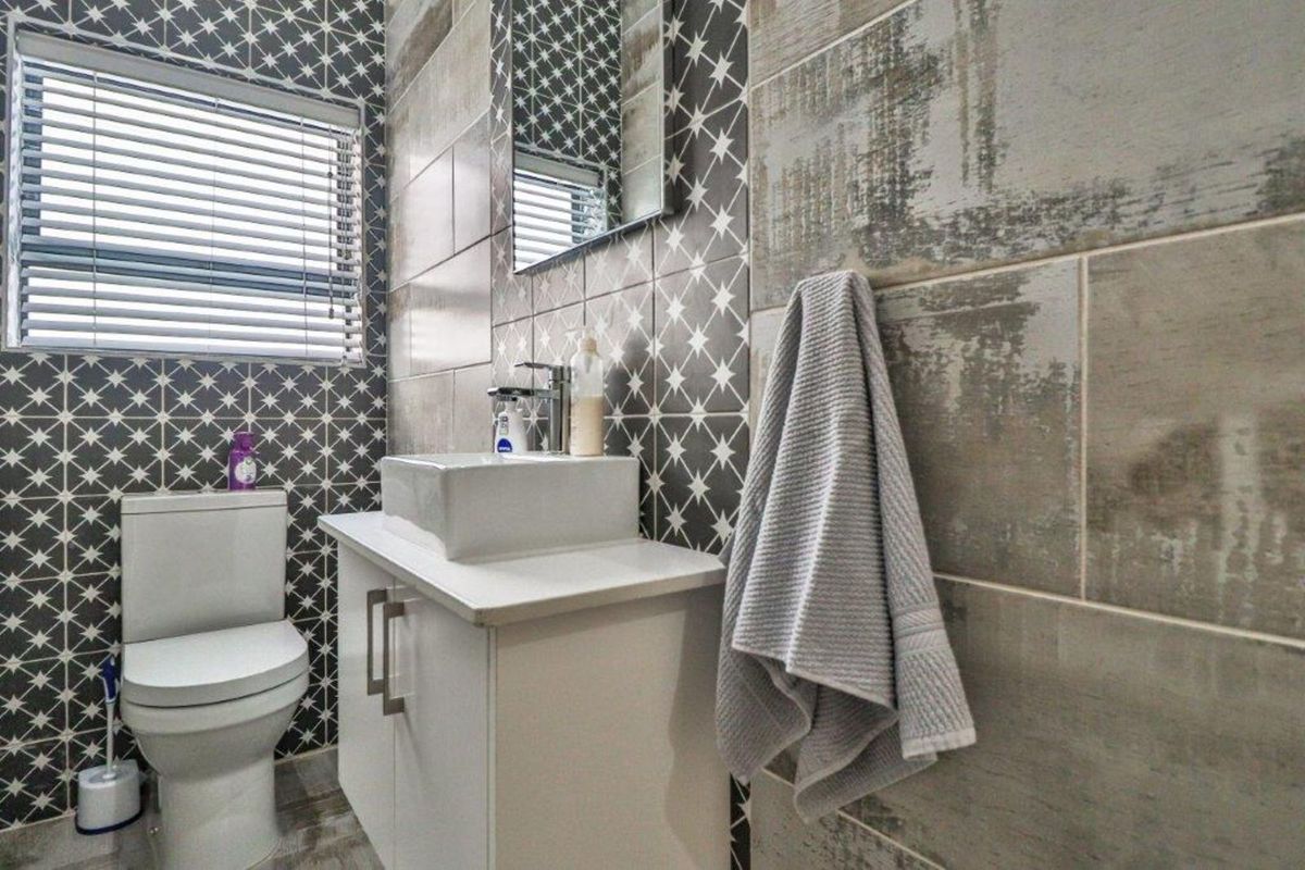 Modern bathroom featuring patterned wall tiles, a contemporary vessel sink vanity, and a sleek toilet.