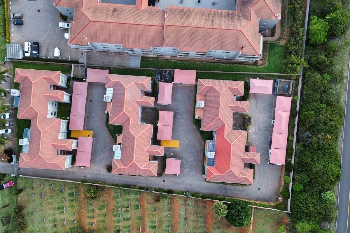 Aerial view of the apartment complex showing the building layout, tiled roofs, parking areas, and surrounding grounds.