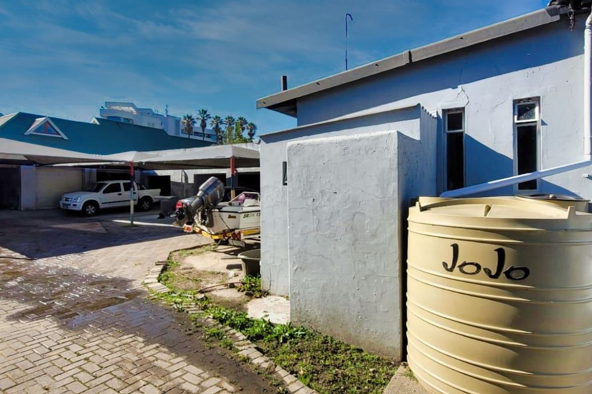 Rear exterior view of the retail property featuring a paved yard, covered parking bays, and a large water storage tank.