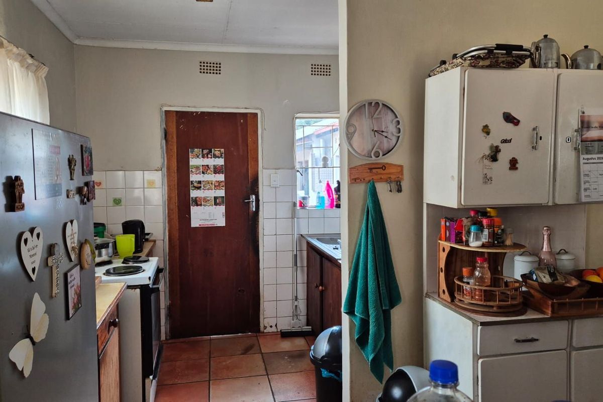 A functional kitchen area featuring tiled flooring, built-in cabinetry, and a rear access door, offering a practical layout for daily meal preparation.
