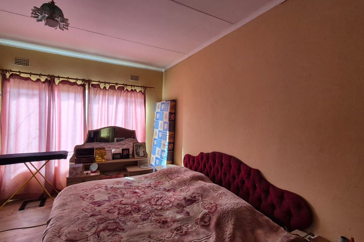 A bedroom featuring a large window with curtains, providing natural light to the space.