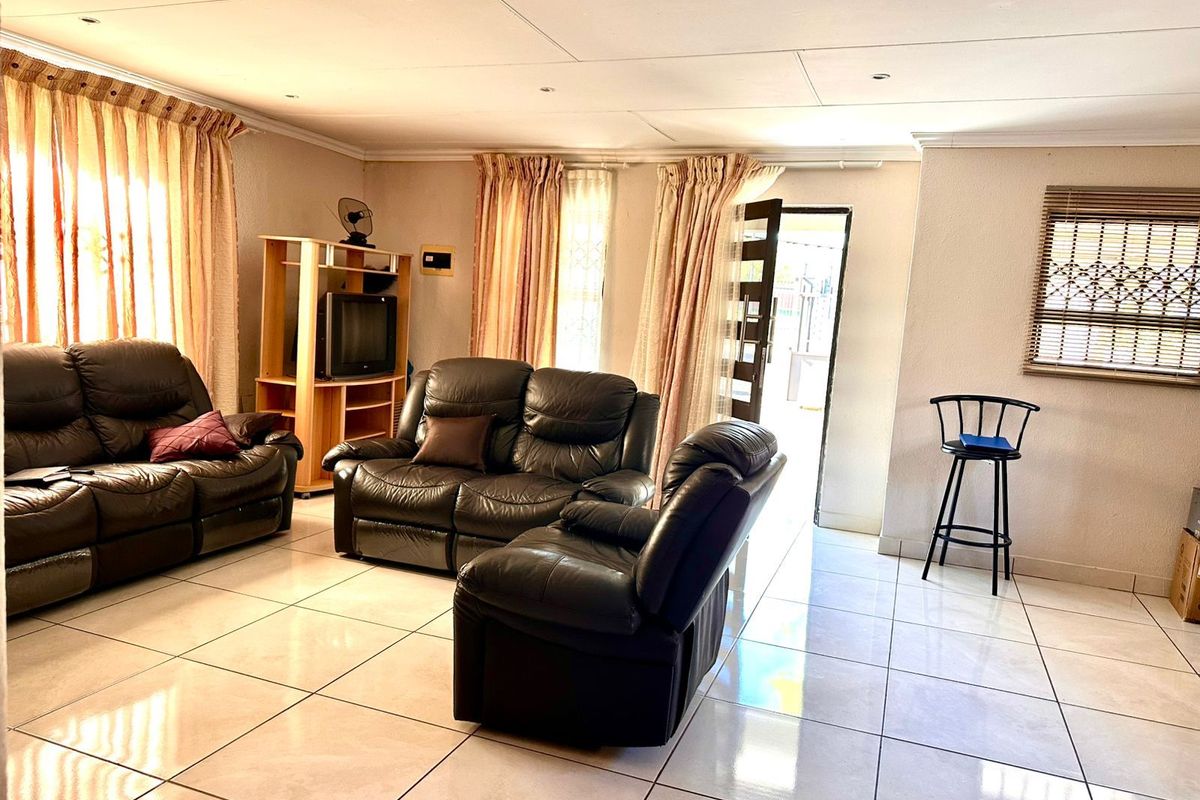 Spacious living room featuring large format floor tiles, recessed ceiling lighting, and direct access to an outdoor area.