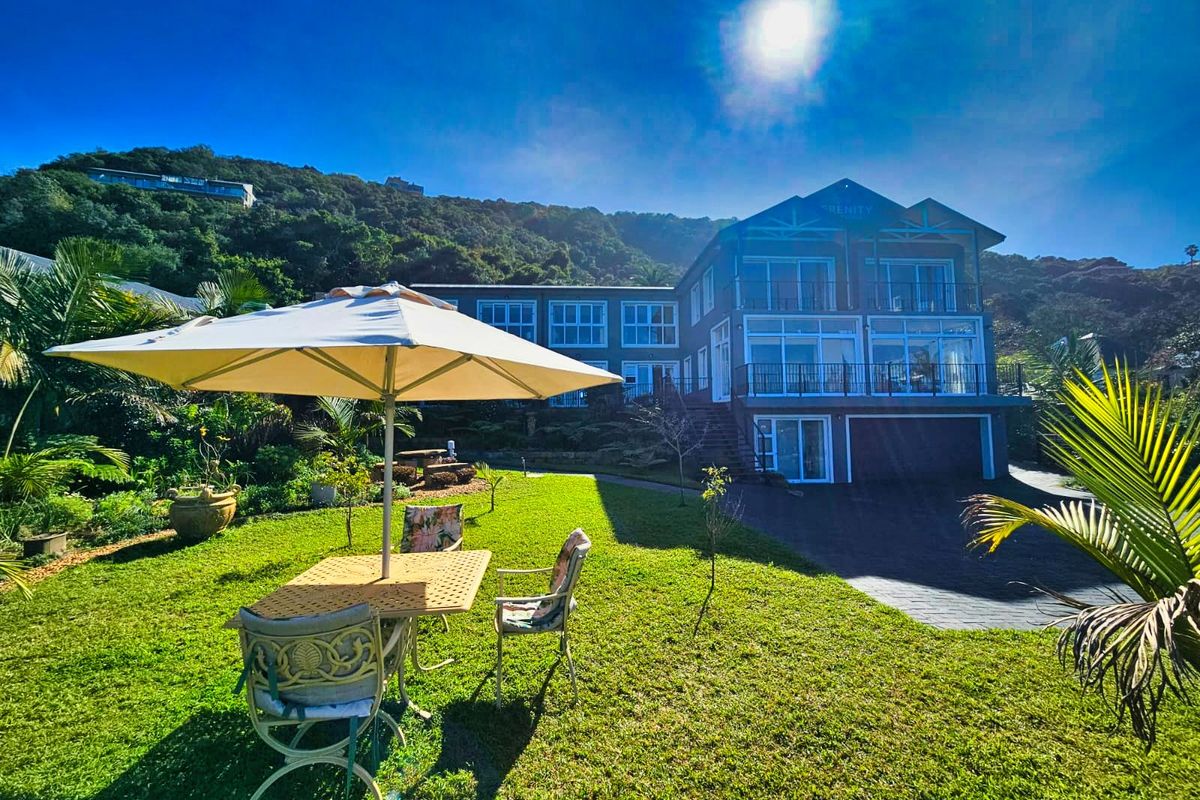 A view of the rear exterior of the multi-story house, featuring a landscaped garden, paved driveway, and balconies overlooking the property.