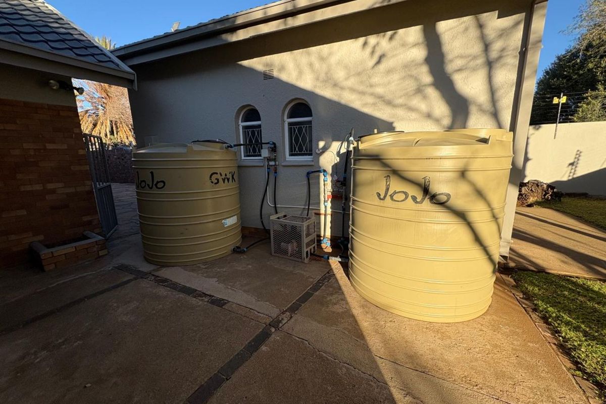 Exterior view of the property featuring two large plastic water storage tanks connected to the building's plumbing system.