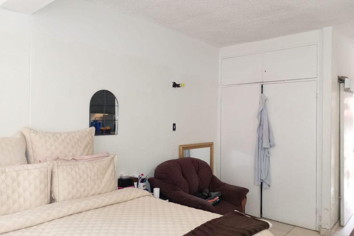 A bedroom featuring built-in floor-to-ceiling storage cupboards and tiled flooring.