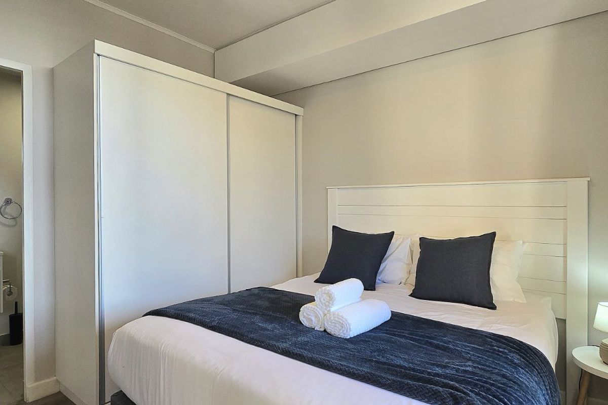 A well-maintained bedroom featuring a built-in wardrobe and an en-suite bathroom with a modern vanity.
