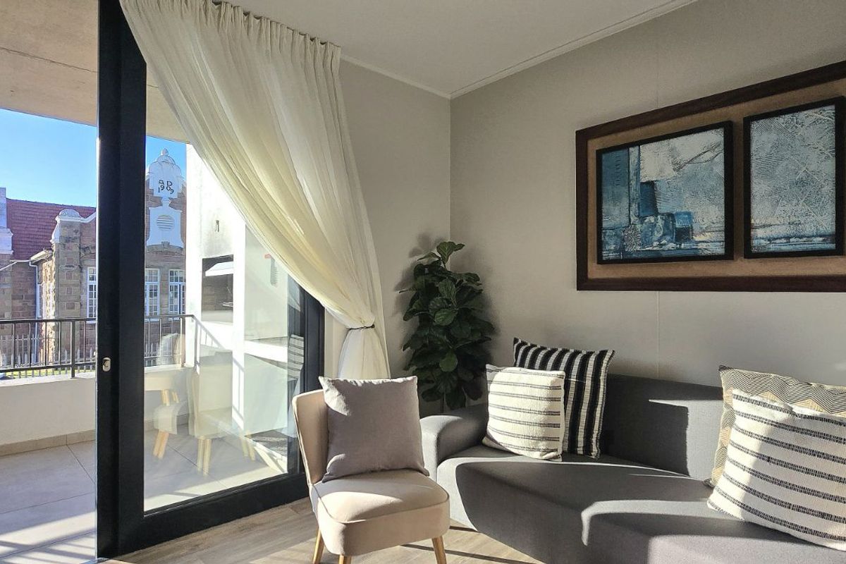 A bright living room featuring large sliding glass doors that open onto a private balcony, providing natural light and outdoor access.
