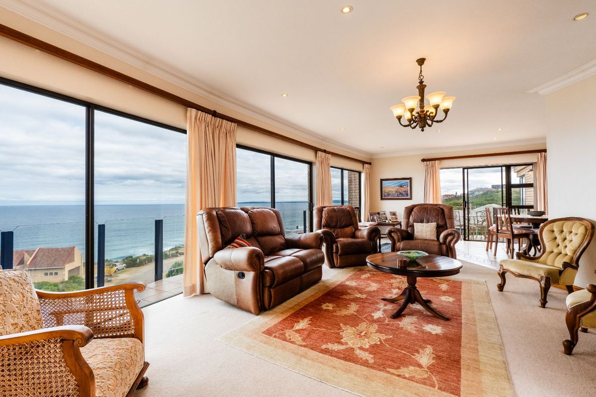 Spacious living area featuring large floor-to-ceiling windows with expansive ocean views, recessed lighting, and a classic chandelier.