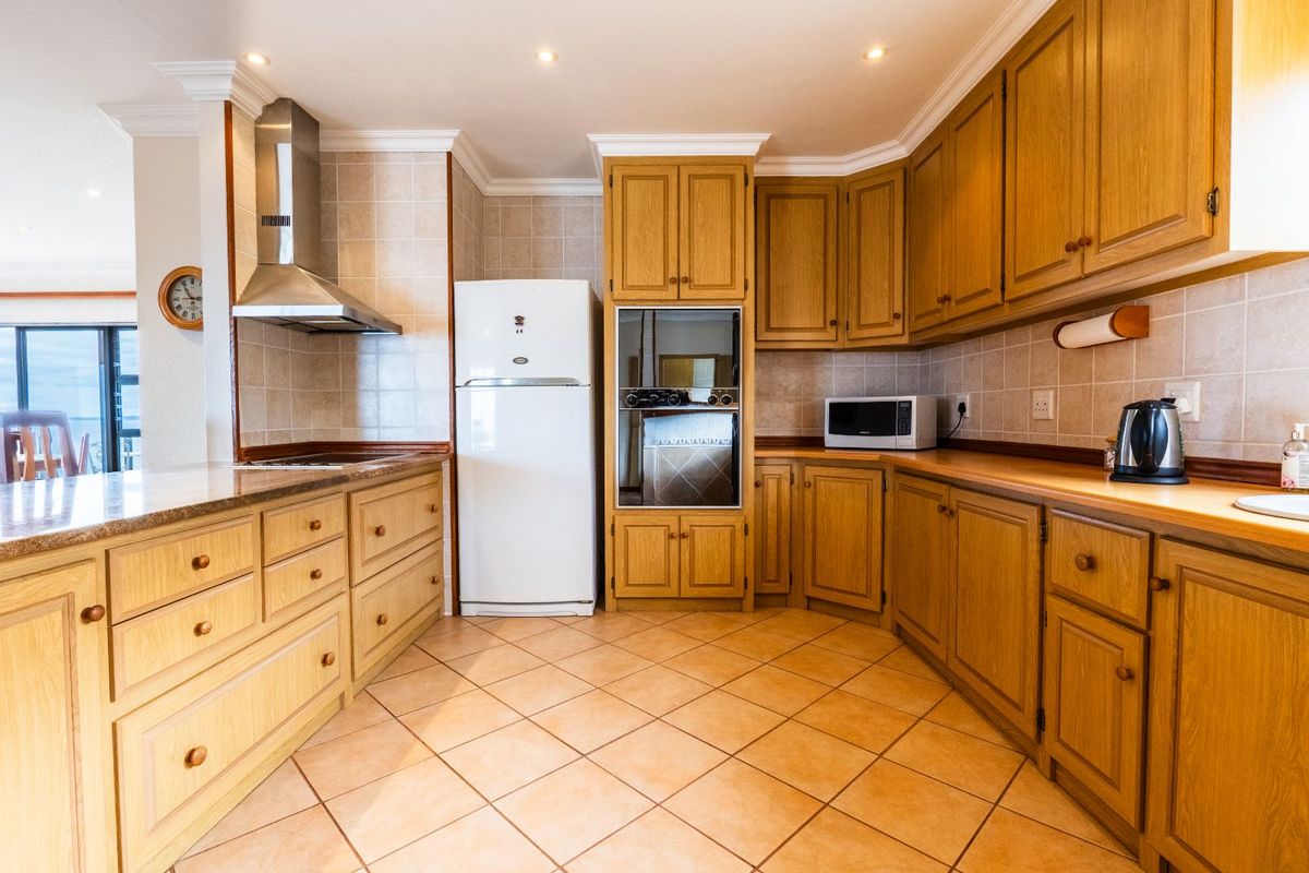 A functional kitchen featuring traditional oak cabinetry, tiled flooring, granite countertops, a stainless steel extractor fan, and a built-in oven.