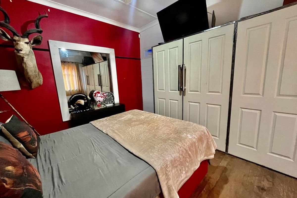 A bedroom featuring built-in wardrobes and a ceiling fan, finished with bold red accent walls.