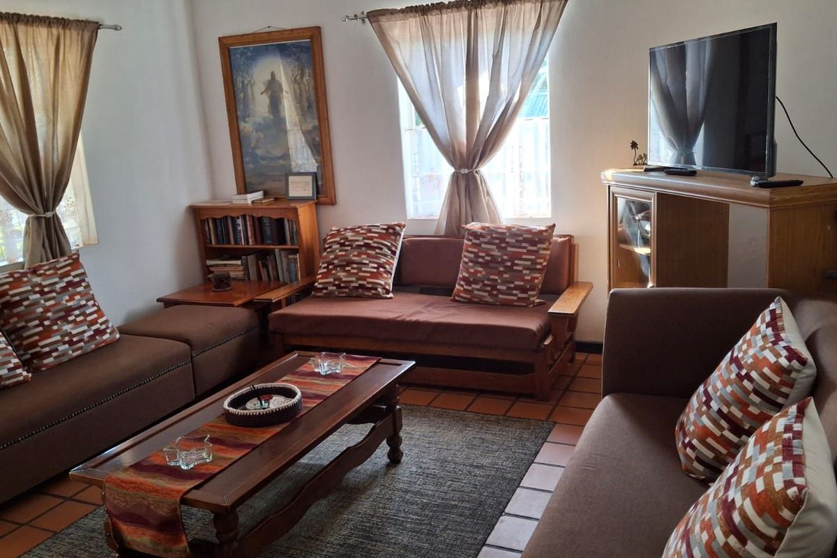 A comfortable living room featuring terracotta floor tiles and natural light from multiple windows.