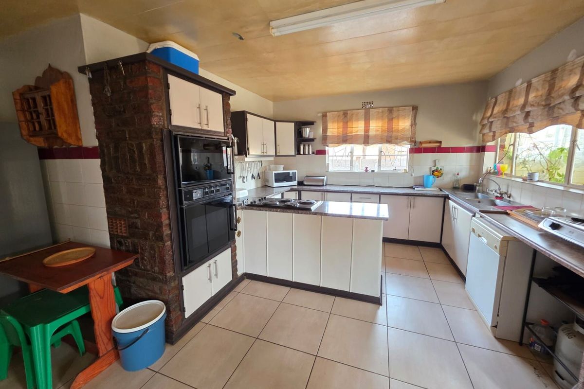 A functional kitchen featuring built-in cabinetry, a brick-encased wall oven, tiled flooring, and a double sink with ample counter space.