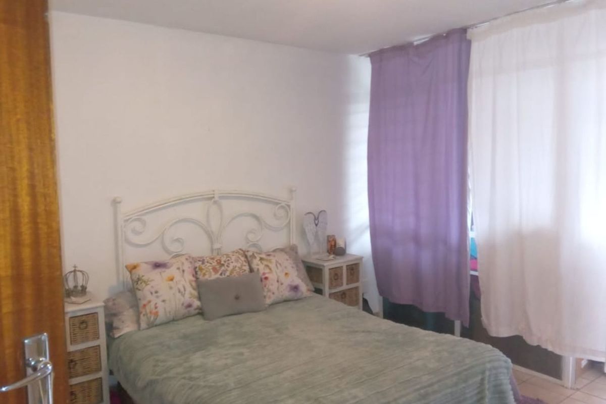 A bedroom featuring tiled flooring and window treatments.